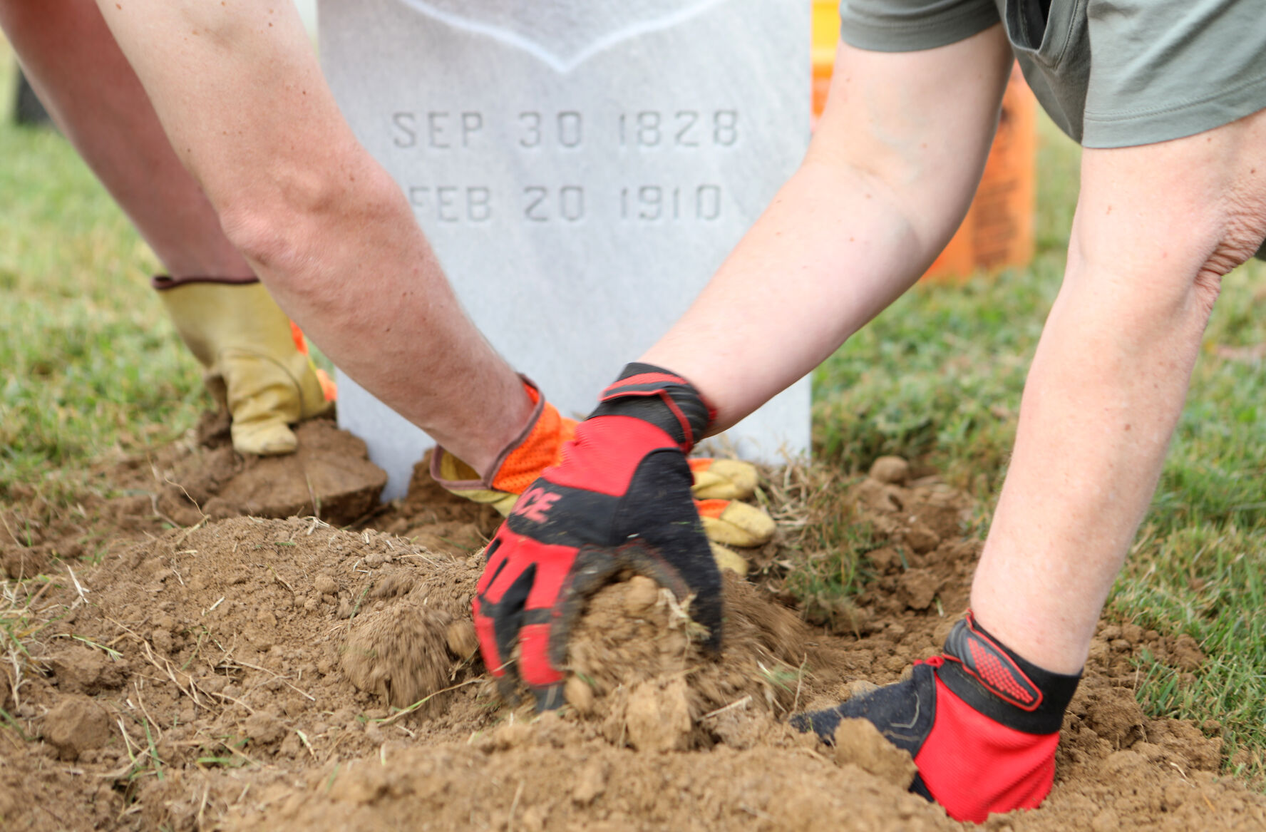 Volunteers pack sod around a headstone